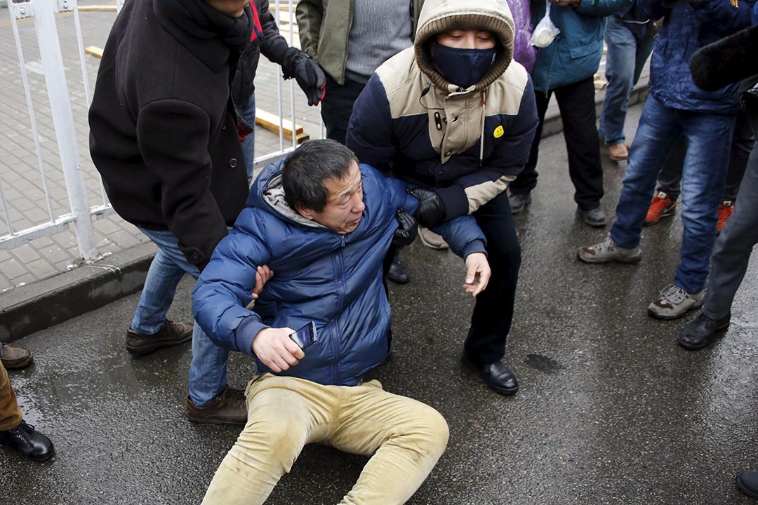 Plainclothes police officers lift a supporter of China's rights lawyer Pu Zhiqiang who was pushed to the ground by police officers near a court where Pu's trial is being held, in Beijing